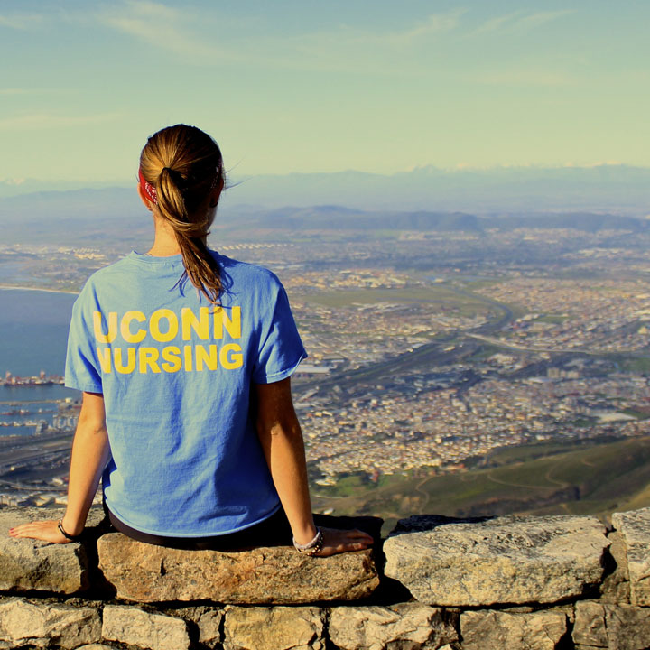 nursing student rests on a stone legde over greece