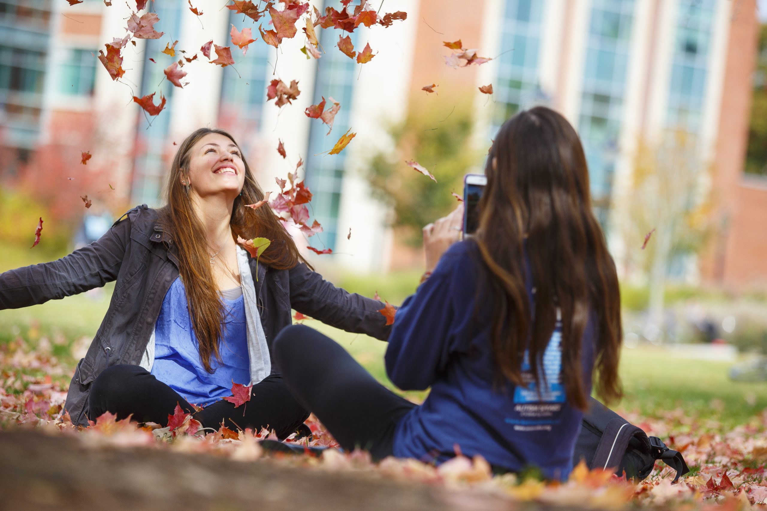 Student tossing leaves into the air